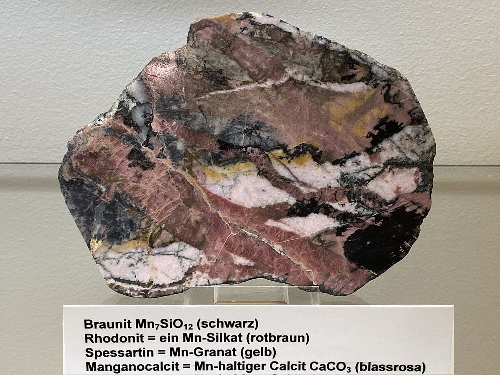 angeschliffen: Braunit, Rhodonit, Spessartin und Manganocalcit B: 15 cm, F: Graubünden| 